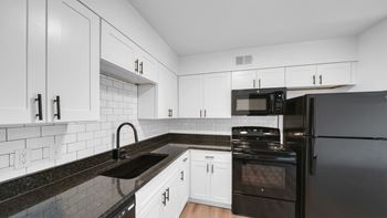 A kitchen with black appliances and white cabinets.